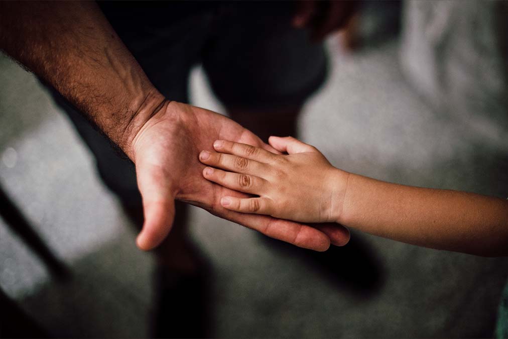 A father holds his child’s hand. Child custody process Australia.