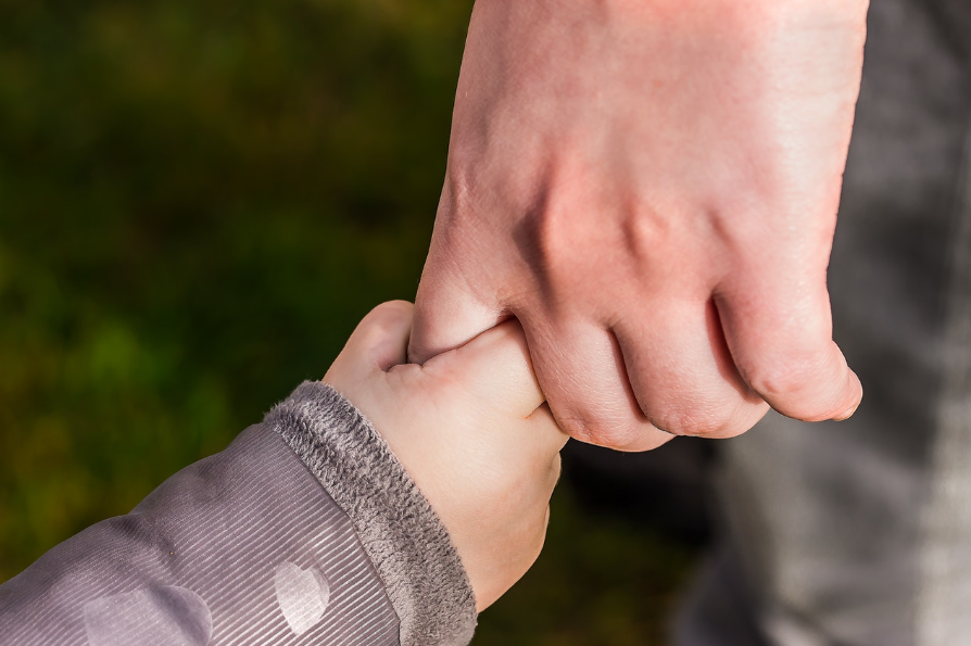 What is a godparent legally? Child holding parent’s hand.