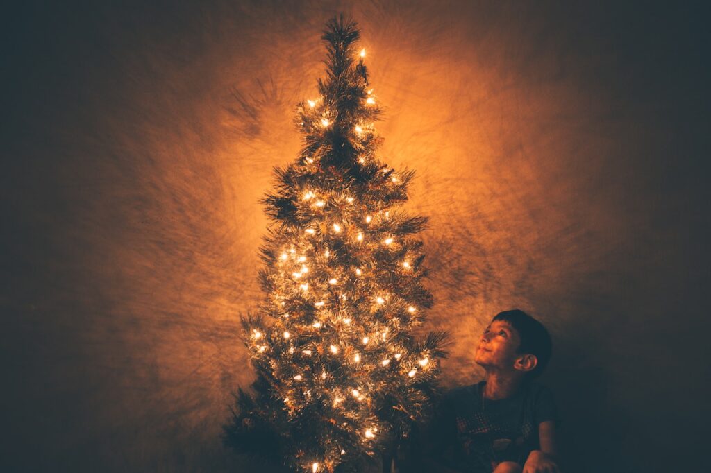 Managing Christmas after divorce. Boy sitting next to Christmas tree. 