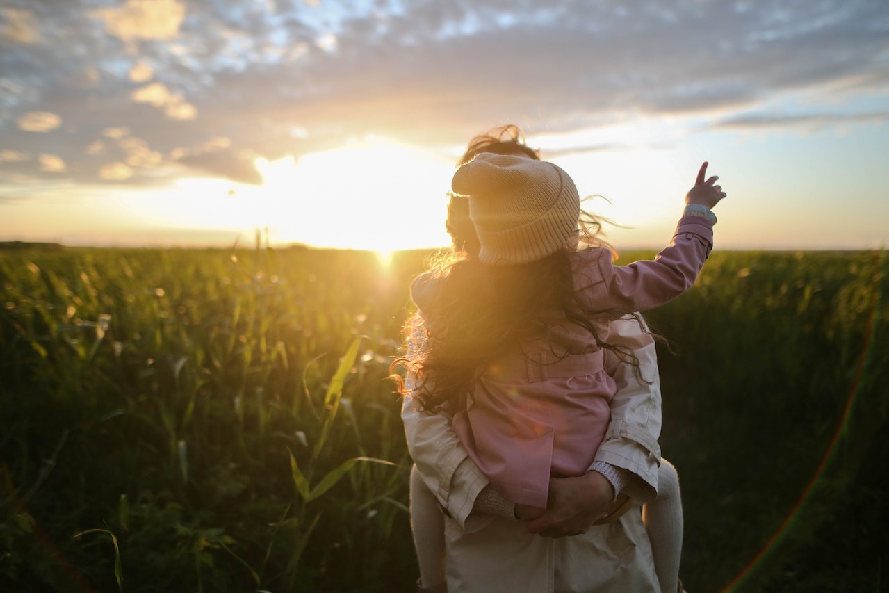 Common types of child custody after divorce. Child on parent’s back at sunset.